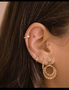 a woman wearing gold ear piercings and an ear ring