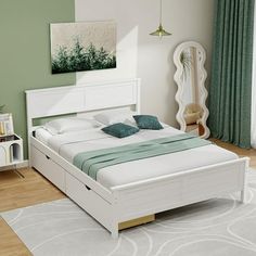 a white bed sitting on top of a wooden floor next to a green painted wall