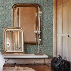 a room with a bed, mirror and purse on the floor in front of it