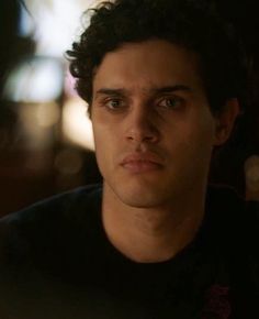 a close up of a person wearing a black shirt and looking at the camera with a serious look on his face