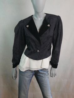 This elegant black cropped blazer has an etched floral pattern, a band collar with velvet lower lapels, and shoulders pads. The jacket has slightly puff sleeves and closes in the front with one button. The blazer is lined in a black satin acetate fabric. Condition: Excellent (Professionally Cleaned ... soft and supple, with no stains, tears, wear spots, or weaknesses in the seams)  Size 12 US, 16 UK Bust = 40 inches (101.6cm) Shoulders = 16.5 inches (41.91cm) Waist = 38 inches (96.52cm) Hemline Formal Black Cropped Jacket With Buttons, Elegant Black Cropped Jacket, Elegant Black Cropped Jacket For Evening, Elegant Black Cropped Jacket For Formal Events, Elegant Black Cropped Jacket For Formal Occasions, Elegant Black Cropped Jacket With Buttons, Elegant Black Cropped Jacket With Button Closure, Semi-formal Black Cropped Jacket For Fall, Black Semi-formal Cropped Jacket For Fall