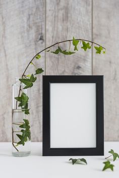 an empty frame next to a plant in a vase