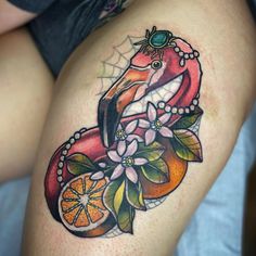 a woman's thigh with an orange and fish tattoo on her leg, which is decorated with flowers and leaves