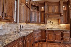 a large kitchen with wooden cabinets and marble counter tops, along with hardwood flooring