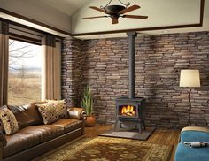 a living room with a couch, chair and fire place inside of it in front of a stone wall