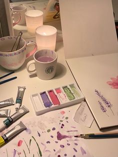 the table is covered with art supplies such as watercolors, pens and paper