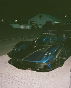 a black sports car is parked on the side of the road at night with its lights on