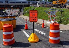 construction signs and cones on the side of an empty road in front of a train