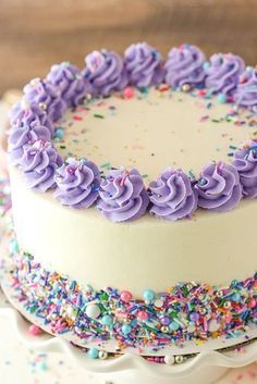 a white cake with purple frosting and sprinkles