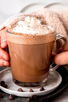 someone holding a cup of hot chocolate with whipped cream