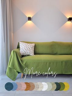 a green couch sitting in front of a white wall with lights on it and a multicolored rug next to it