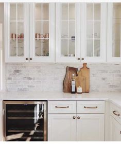 a kitchen with white cabinets and wooden cutting board