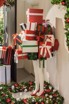 christmas presents piled on top of each other in front of a mannequin dressed as a woman