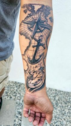 a man's arm with a compass and an anchor tattoo on the left forearm