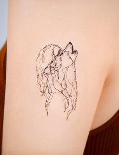 a woman's back with a tattoo of two dogs on her left shoulder and the other side of her arm