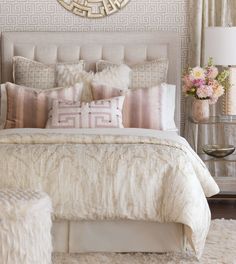 a bedroom with a bed, pillows and a mirror on the wall above it's headboard