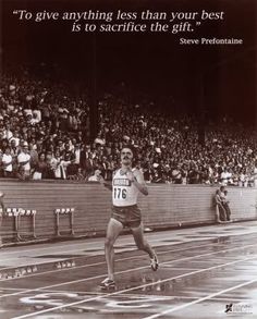 a man running on a track in front of an audience with a quote above him