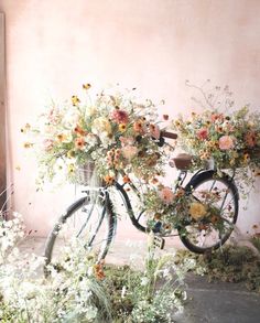 a bicycle with flowers on the back parked in front of a wall