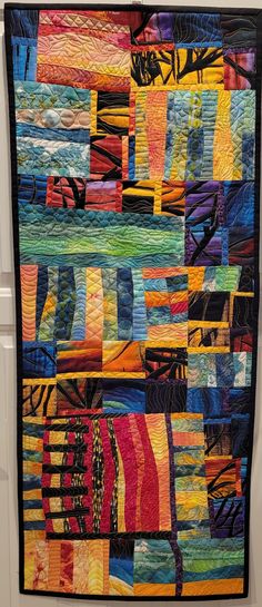 a multicolored quilt hanging on the wall