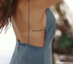 the back of a woman's neck with a small tattoo on her left side