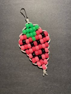 an ornament made out of candy beads on a gray surface with a black hook