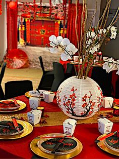 the table is set with plates, cups and vases for chinese new year's eve