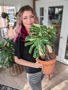 a woman is holding a potted plant in her hand and smiling at the camera