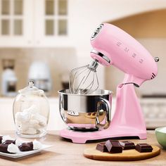 a pink mixer sitting on top of a kitchen counter next to chocolates and marshmallows