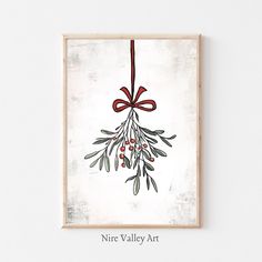 a painting hanging on the wall with a red bow and berries tied to it's side