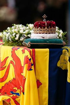 a table topped with a yellow and blue cloth covered tablecloth next to a crown