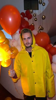 a man in a yellow raincoat holding balloons