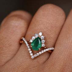 a woman's hand with a diamond and emerald ring