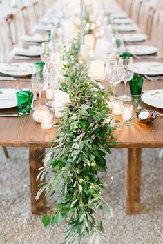 the table is set with candles and greenery