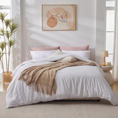 a bed with white sheets and pillows in a room next to a window, potted plant