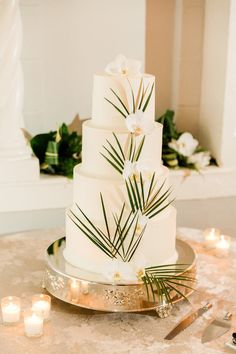 a wedding cake with white flowers and palm leaves