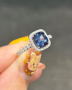 a woman's hand holding an engagement ring with a blue diamond in the center