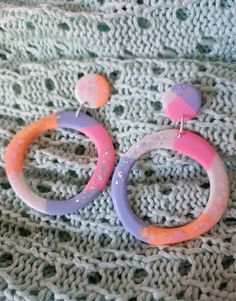 two pairs of colorful hoop earrings sitting on top of a blanket