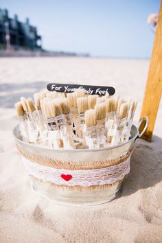 a bucket full of toothbrushes sitting in the sand