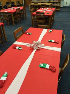 the table is set with red and white cloths, silver bows, and green napkins