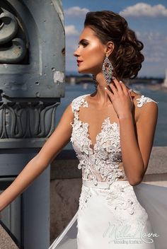 a woman in a white wedding dress posing for the camera with her hand on her shoulder