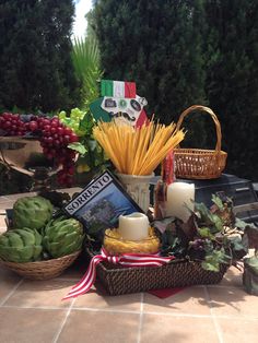 a table topped with baskets filled with food and candles next to other foods on top of a tile floor