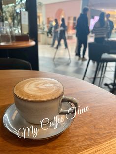 a cappuccino sitting on top of a wooden table in a coffee shop