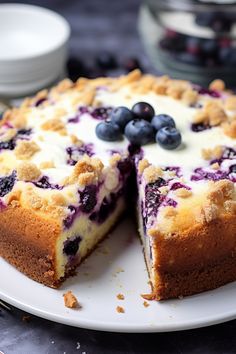 a blueberry cheesecake on a white plate with one slice cut out and ready to be eaten