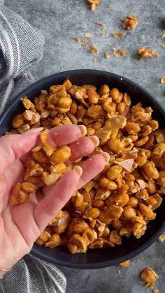 a hand reaching for nuts in a bowl