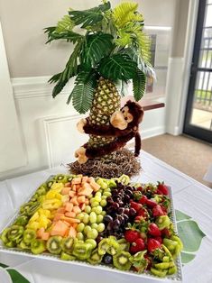 there is a tray with fruit and a monkey sitting on top of the platter