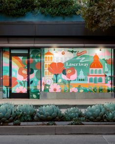 a store front with an advertisement on the side and cactus plants in front of it