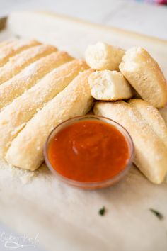 bread sticks and dipping sauce on a cutting board