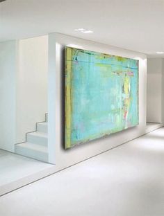 a large painting hanging on the wall in a room with white walls and flooring