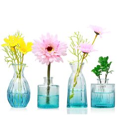 three vases filled with different colored flowers on a white surface, one is empty and the other has water in it