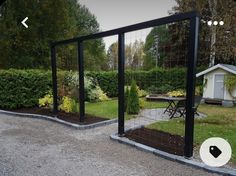 an open gate in the middle of a driveway with trees and bushes around it,